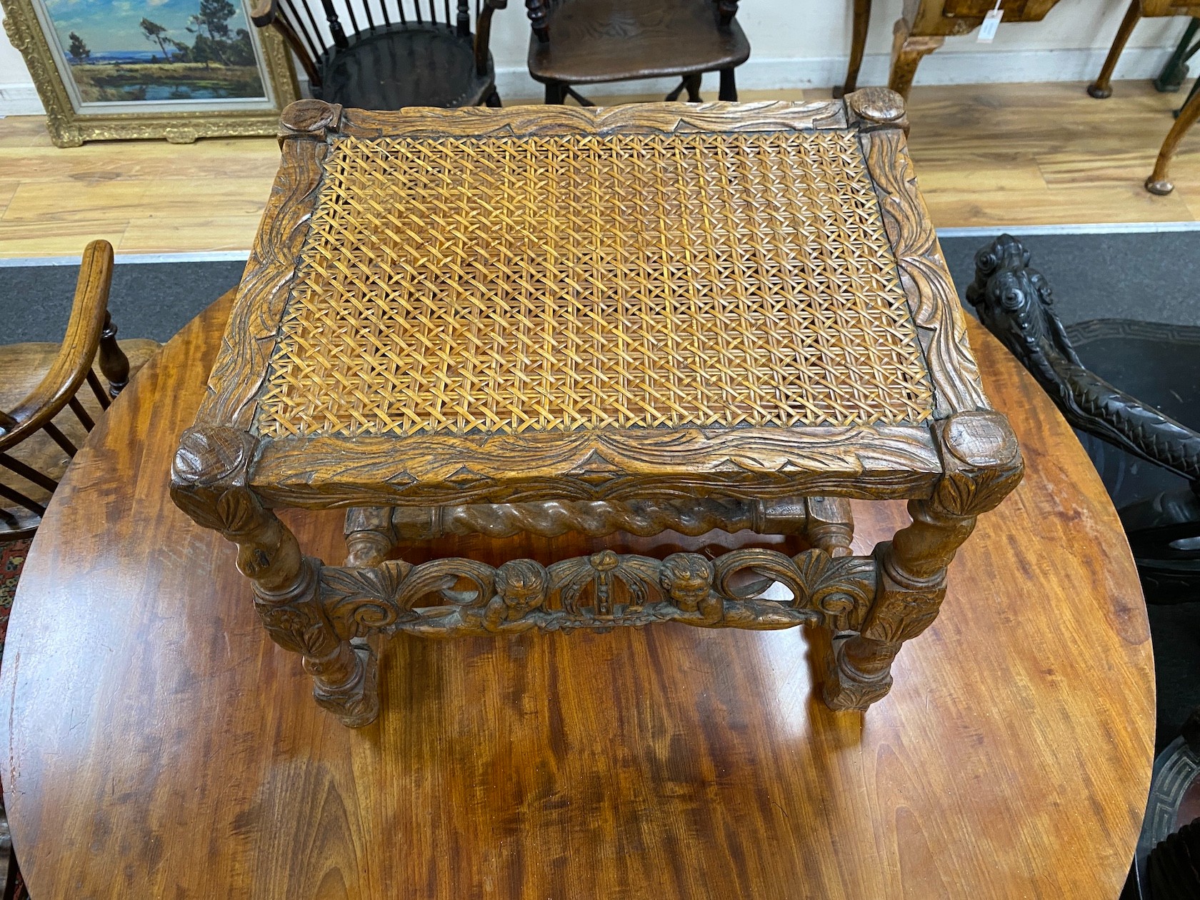 A Jacobean revival carved oak cane seat stool, width 52cm, depth 39cm, height 43cm.